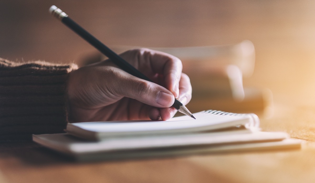 Hands and an open notebook on a table.