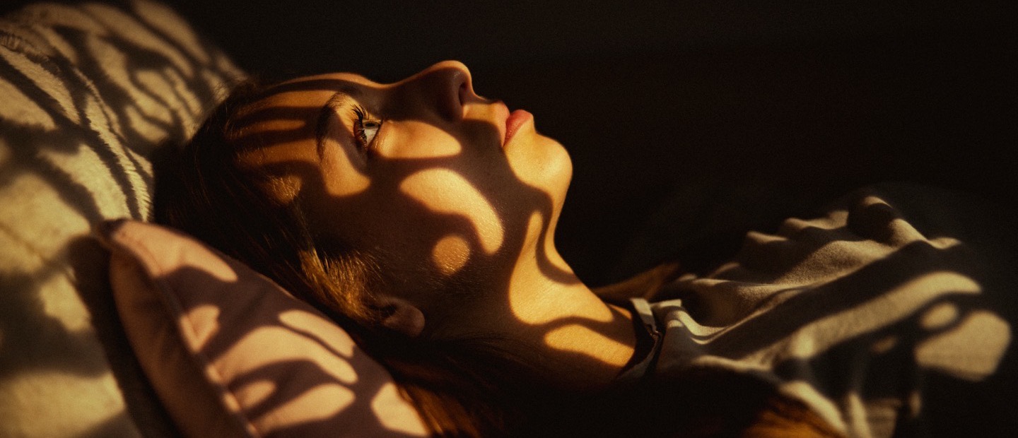 Someone resting on a pillow with dappled morning light across them.