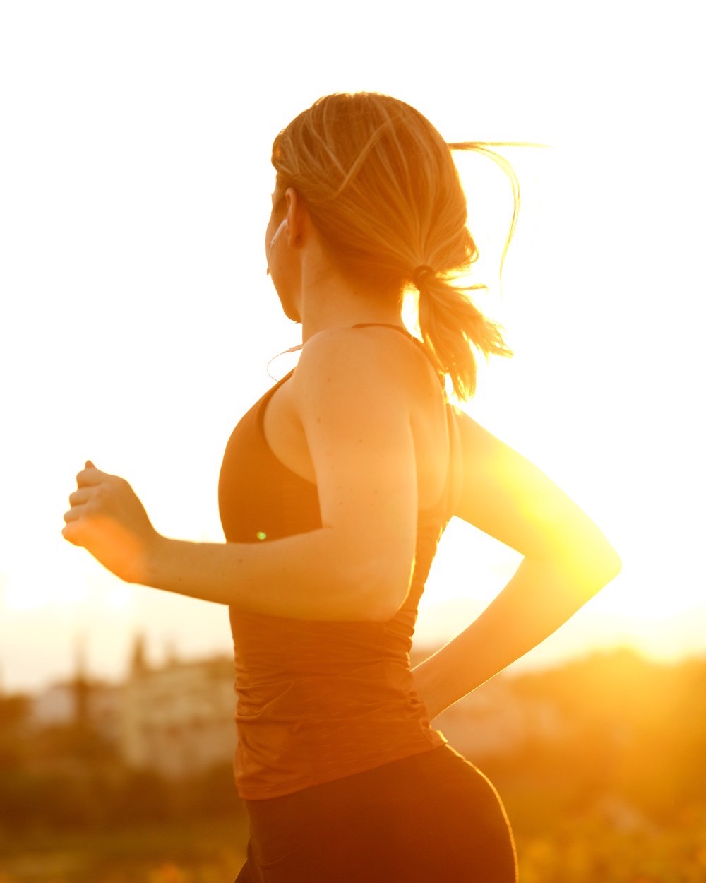 A runner at first light, backlit, cropped at the shoulders.