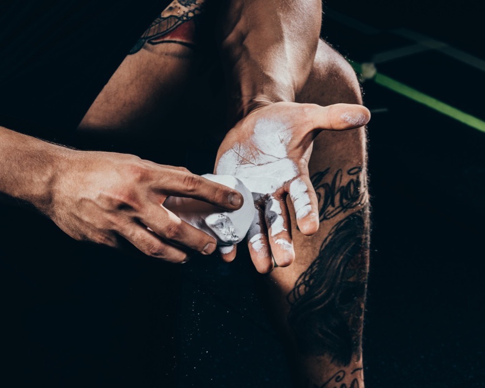 Hands on a bar, chalk dust, movement blurred.